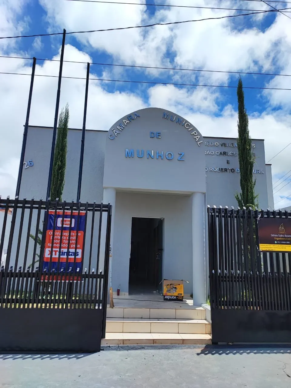 Fachada da Câmara Municipal de Munhoz após a pintura, com gradil e céu azul