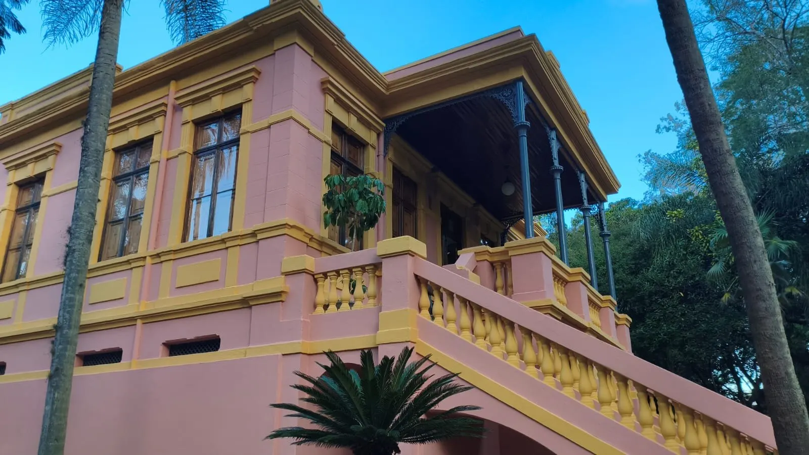 Escadaria com balaústres amarelos e varanda com colunas de ferro