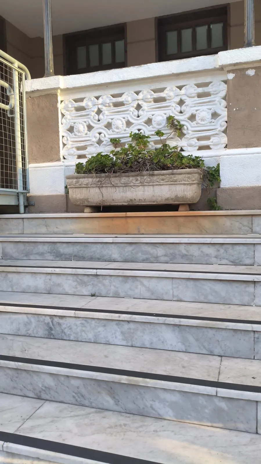 Gradil ornamental branco junto à escadaria de mármore