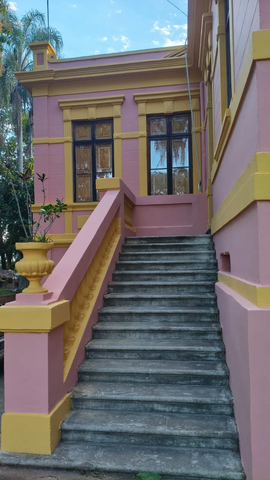 Escadaria de pedra com guarda-corpo pintado em rosa e amarelo