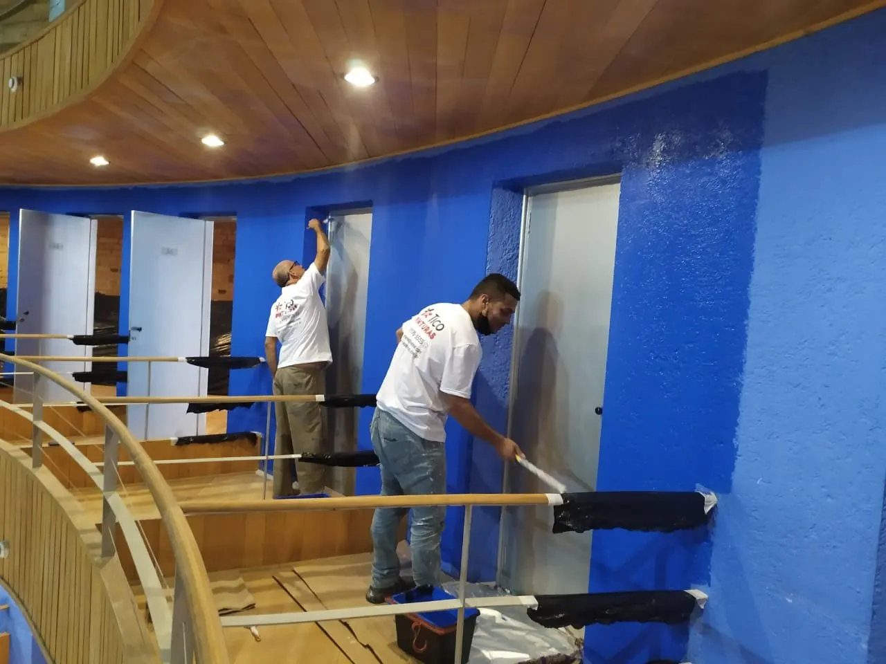 Pintores da Tico Pinturas aplicando tinta azul nas paredes das galerias