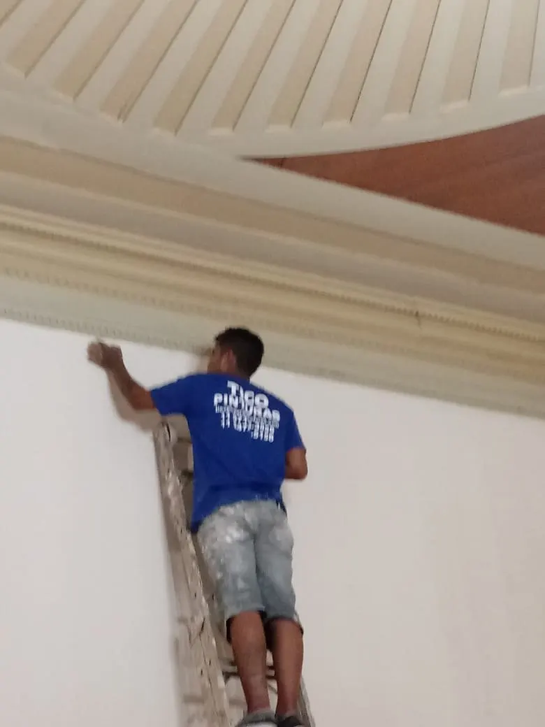Pintor fazendo recorte junto à sanca ornamentada