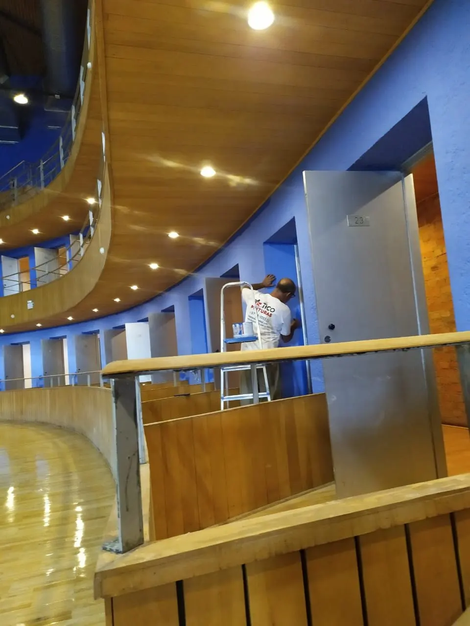 Pintor trabalhando junto às portas das galerias do teatro