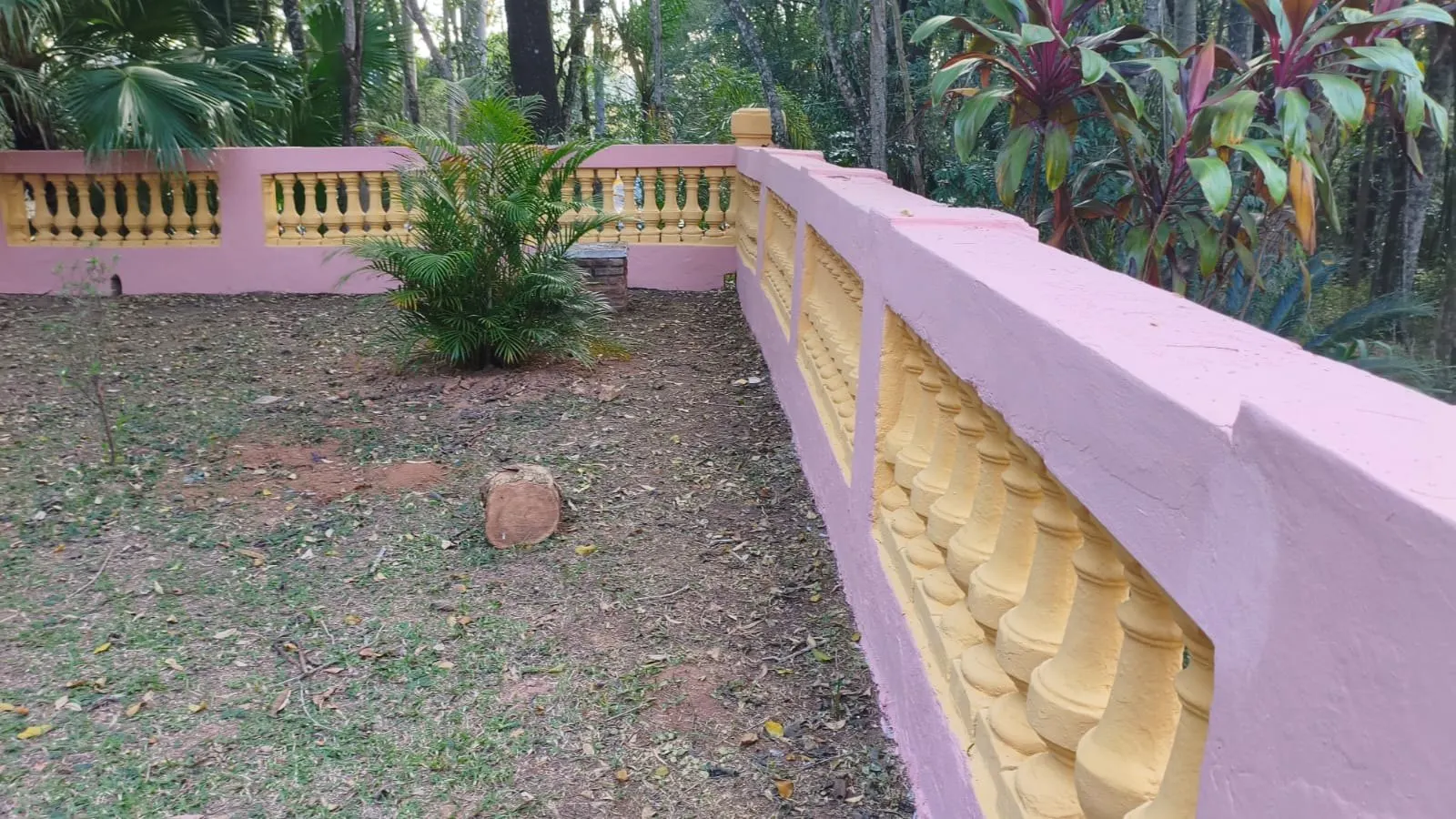 Mureta com balaústres repintados no jardim do palacete