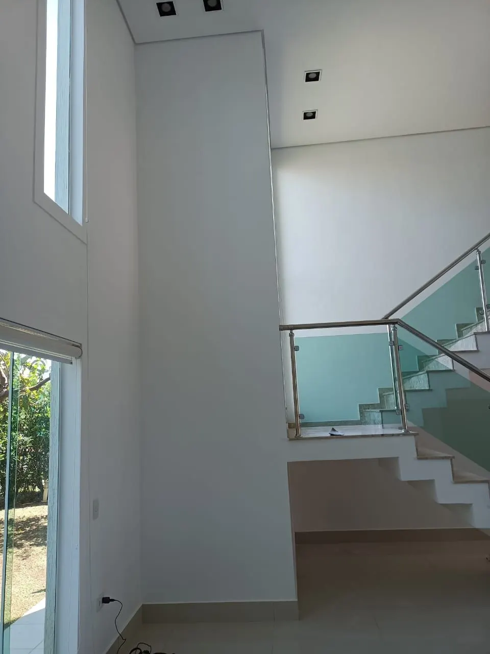 Pé-direito duplo com escada e guarda-corpo de vidro pintado em branco