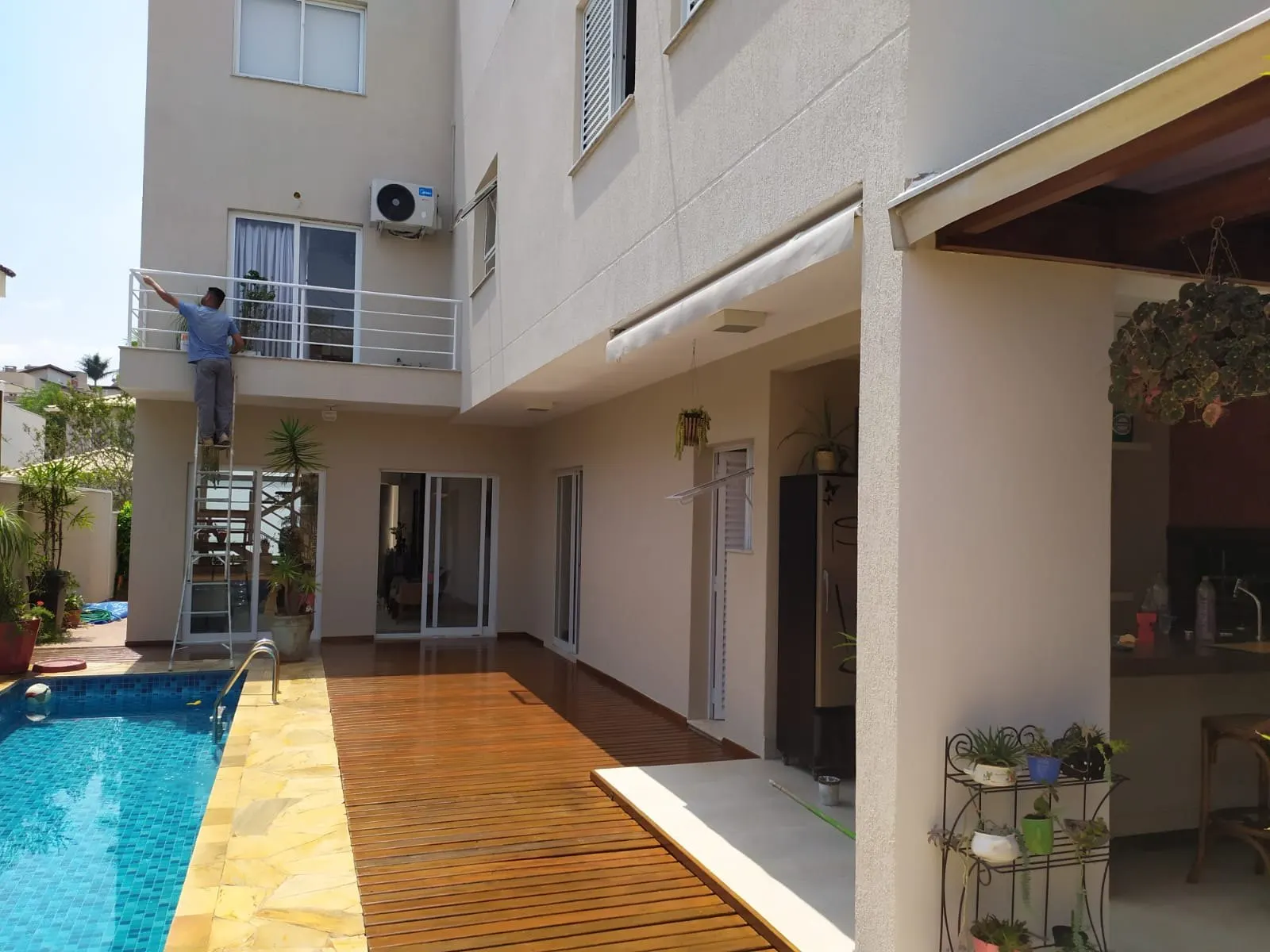Pintor finalizando a fachada dos fundos ao lado da piscina