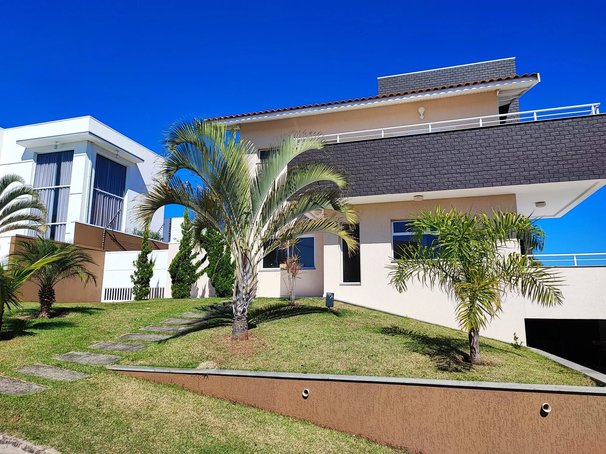 Casa em Itupeva com fachada clara, palmeiras e céu azul
