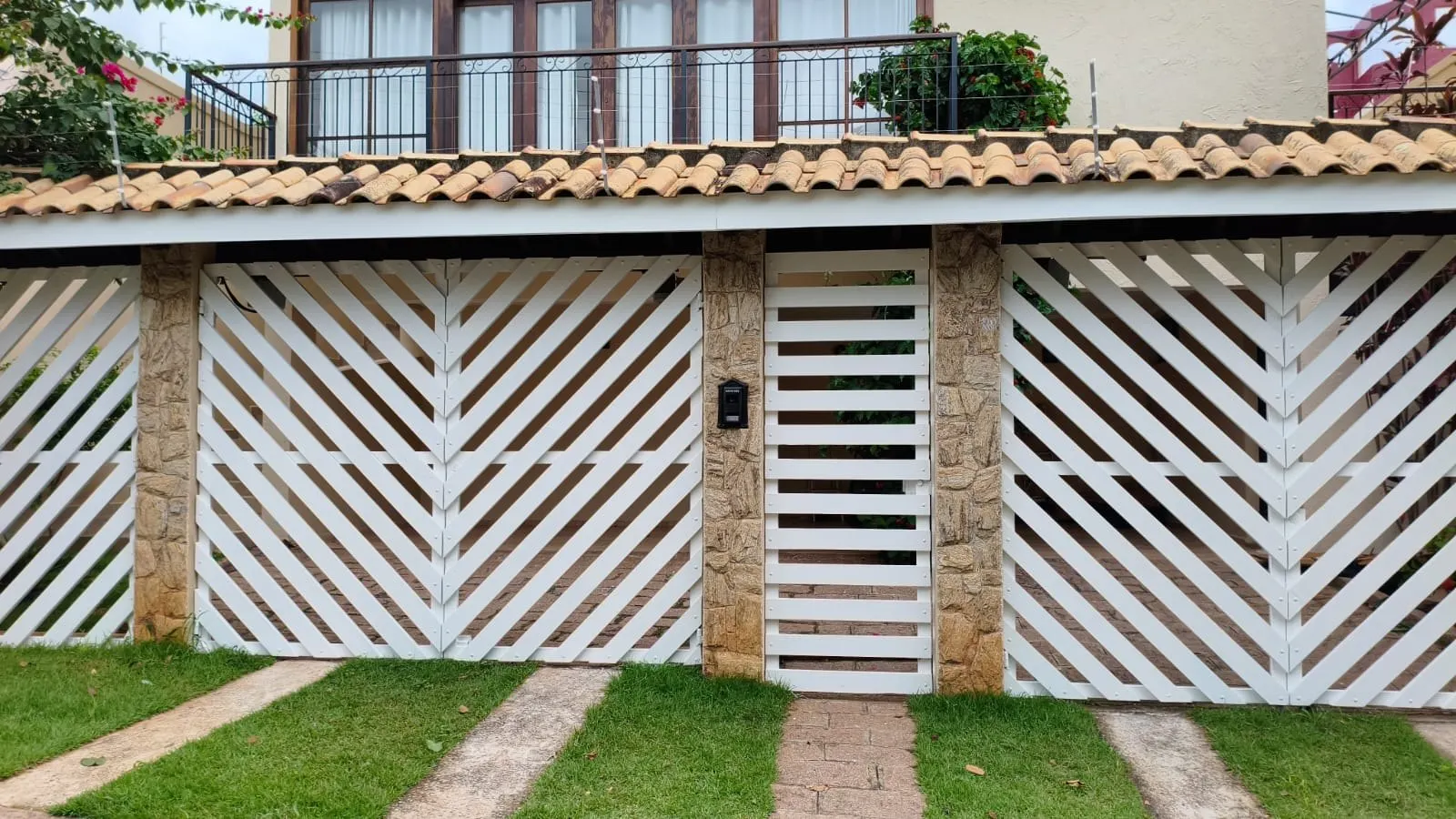 Muro com gradil branco e colunas de pedra repintados